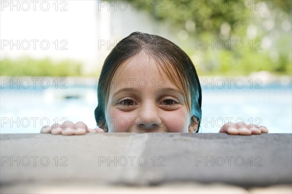 Girl peeking over edge of swimming pool. Date : 2008