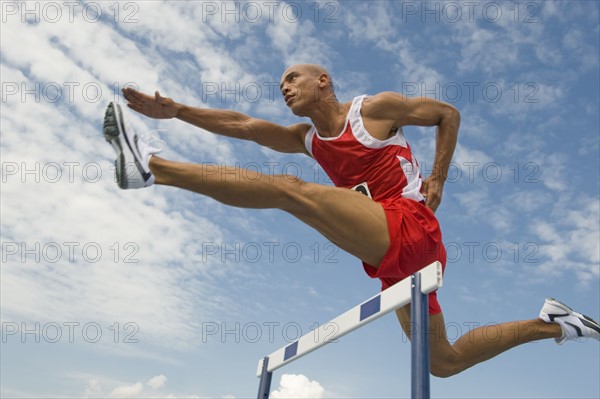 Runner jumping over hurdle.