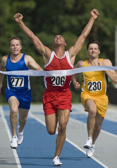 Runner breaking through finish line.