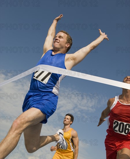 Runner breaking through finish line.