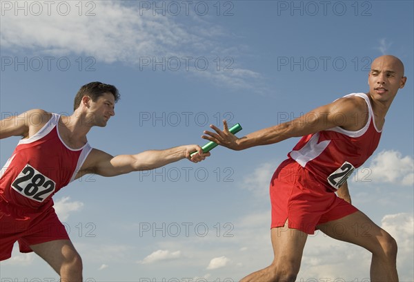 Runner passing baton to teammate.