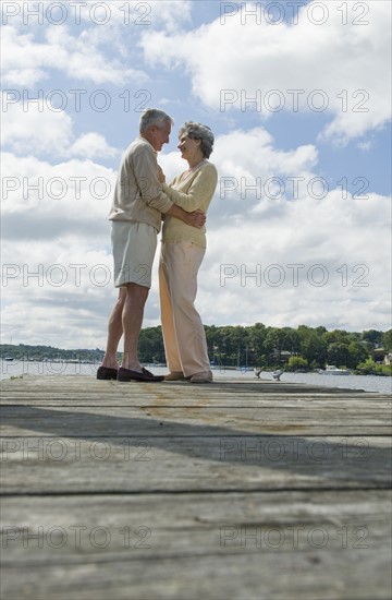 Senior couple hugging on dock.
