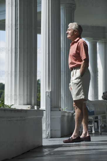 Senior man standing on porch.