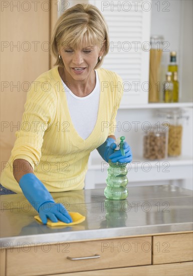 Woman cleaning kitchen counter.