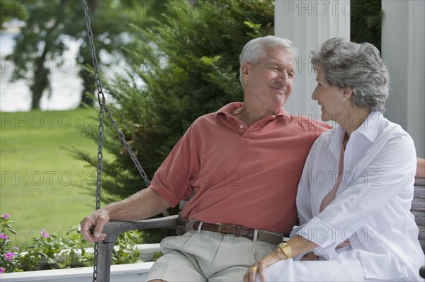 Senior couple sitting on porch swing.