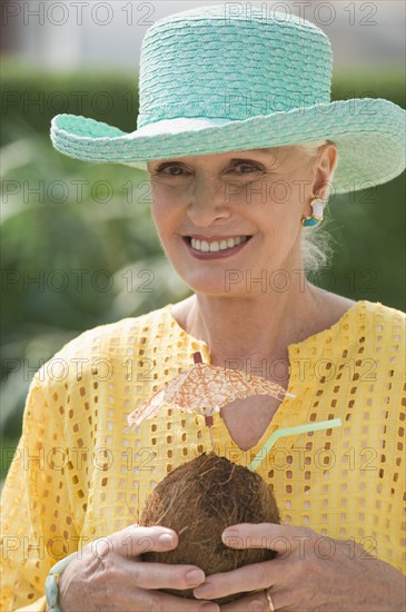 Senior woman holding tropical drink.