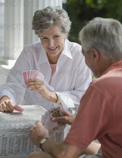 Senior couple playing card game on porch.