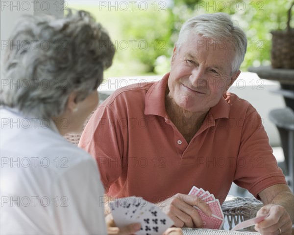 Senior couple playing card game on porch.