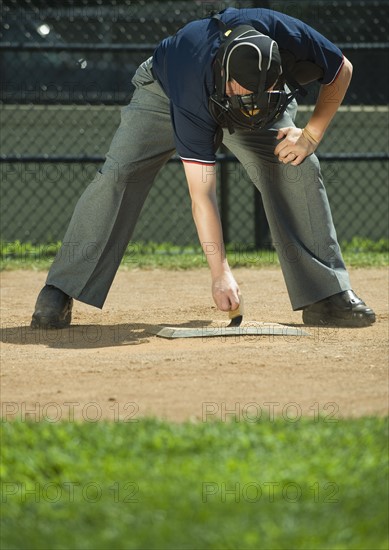 Baseball umpire sweeping home plate.