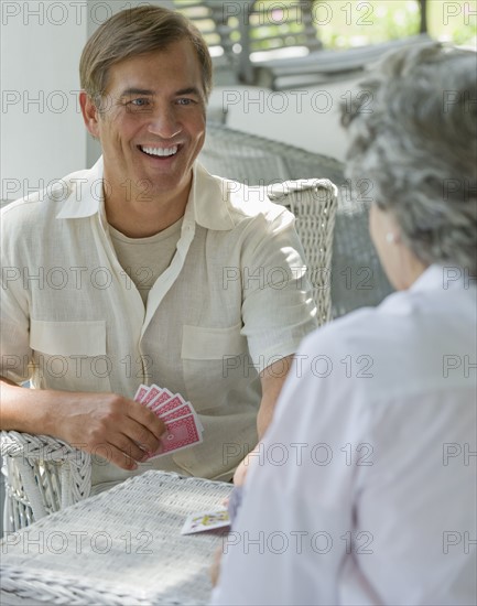 Mother and adult son playing card game on porch.