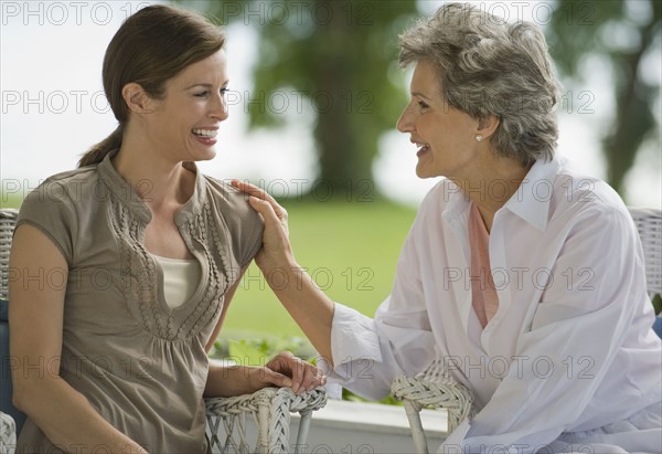 Mother and adult daughter talking on porch.