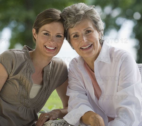 Mother and adult daughter posing outdoors.