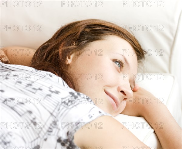 Teenage girl daydreaming on sofa. Date : 2008