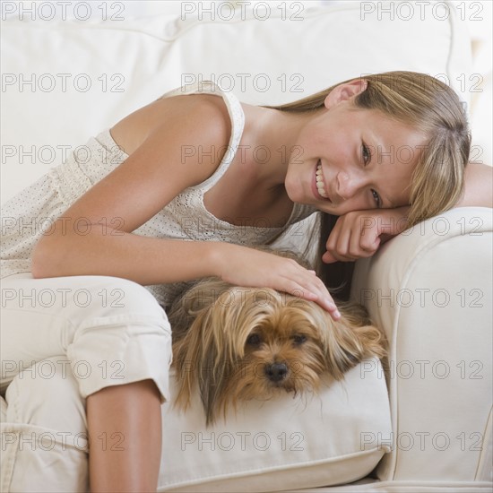 Girl hugging dog on sofa.