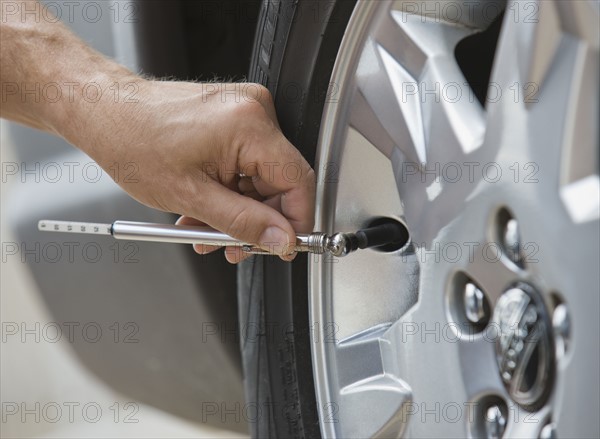 Man checking car tire pressure.