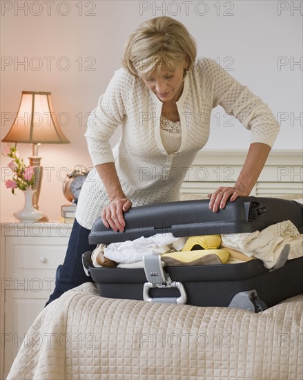 Woman packing full suitcase.