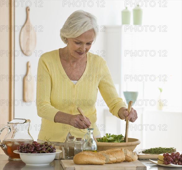 Senior woman tossing salad.