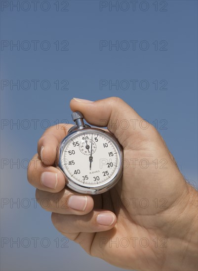 Close up of hand holding stopwatch.