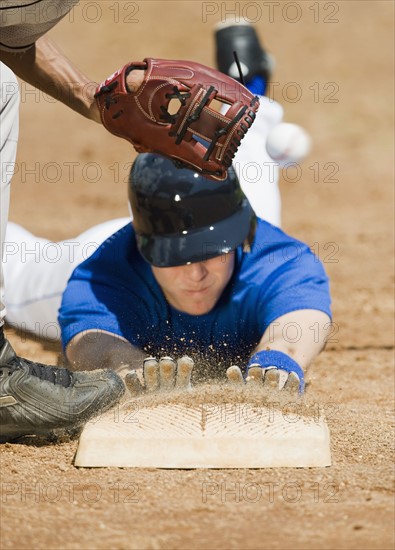 Baseball player sliding into home base.