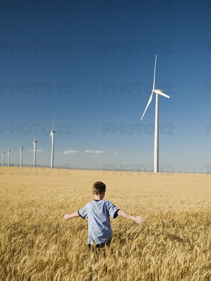 Boy running through field on wind farm. Date : 2008
