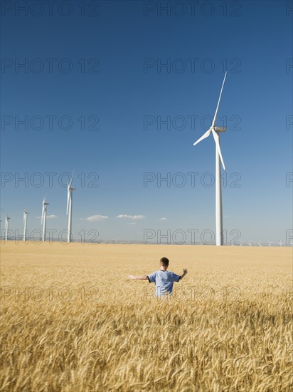 Boy running through field on wind farm. Date : 2008