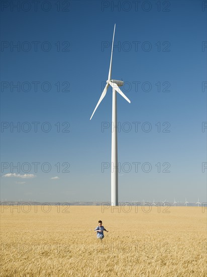 Boy running through field on wind farm. Date : 2008