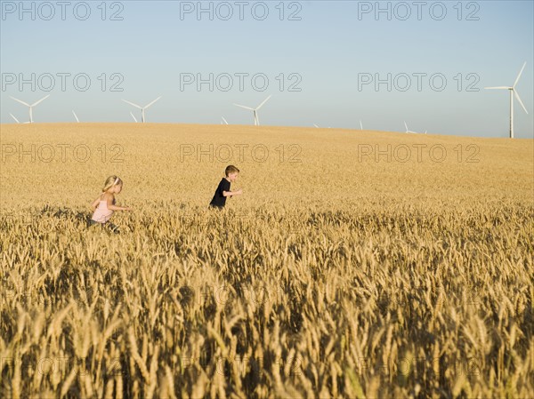 Children running through tall wheat field on wind farm. Date : 2008