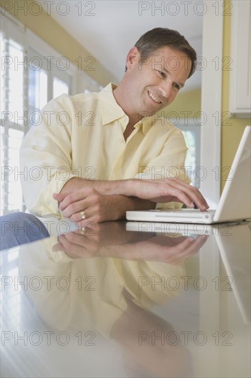 Man looking at laptop in kitchen. Date : 2008