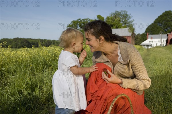 Mother and baby daughter picking strawberries. Date : 2008