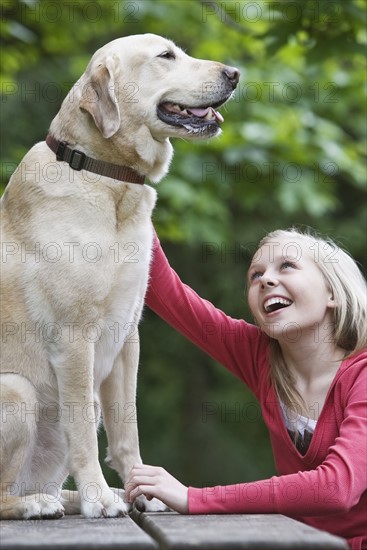 Girl petting dog sitting on picnic table. Date : 2008