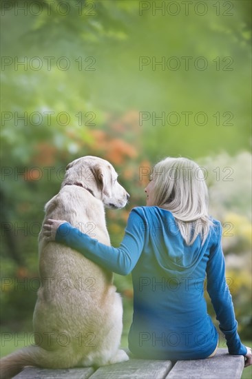 Girl and dog sitting together on picnic table. Date : 2008