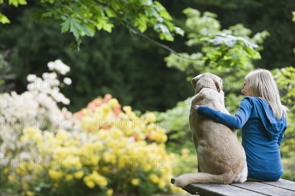 Girl and dog sitting together on picnic table. Date : 2008