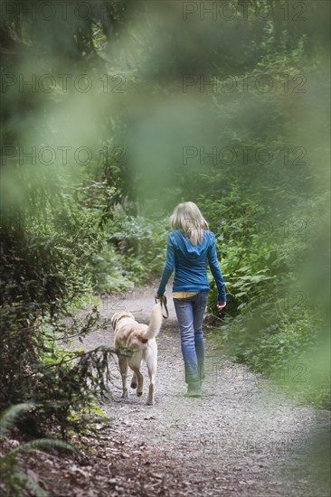 Girl walking dog on forest path. Date : 2008