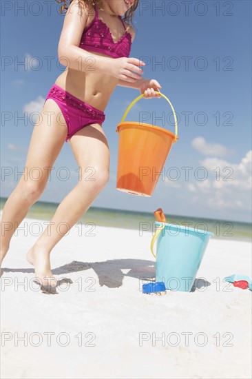 Girl playing with sand buckets on beach. Date : 2008