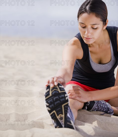 Runner stretching on beach. Date : 2008