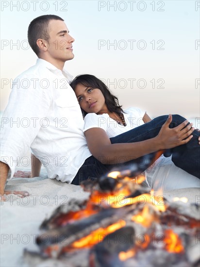 Young couple relaxing by campfire on beach. Date : 2008