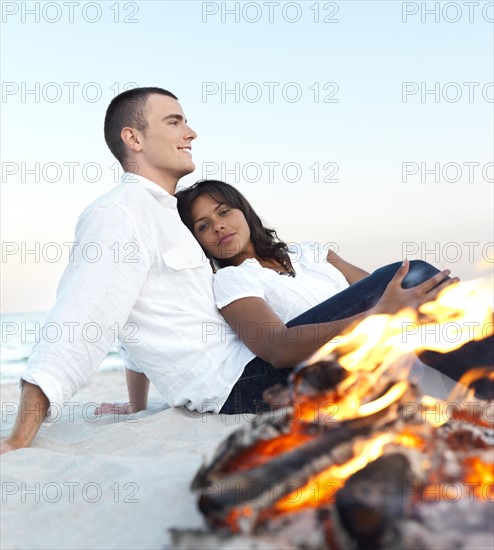 Young couple relaxing by campfire on beach. Date : 2008