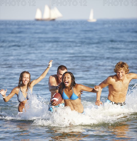 Young friends playing football in ocean. Date : 2008