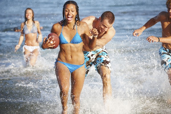 Young friends playing football in ocean. Date : 2008