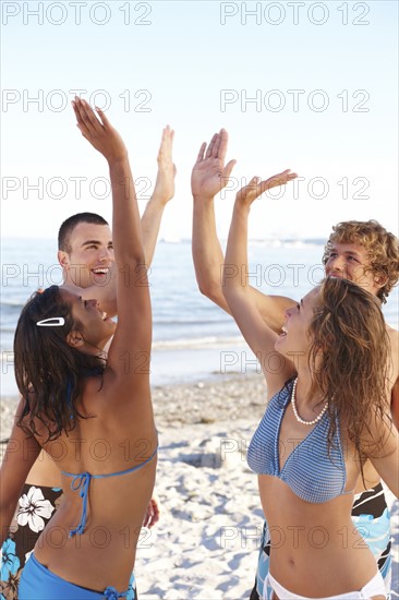 Young friends high fiving on beach. Date : 2008