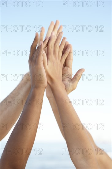 Young friends high fiving on beach. Date : 2008