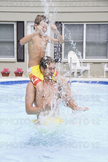 Father and son splashing in swimming pool. Date : 2008