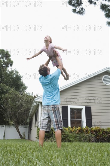 Father lifting daughter in backyard. Date : 2008