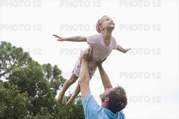 Father lifting daughter in backyard. Date : 2008