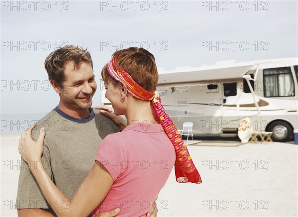 Couple hugging by motor home on beach. Date : 2008