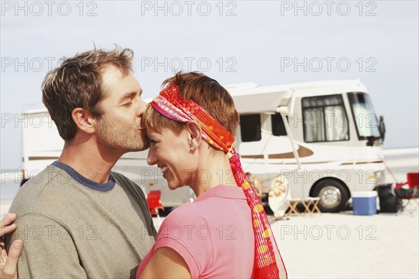 Couple kissing by motor home on beach. Date : 2008