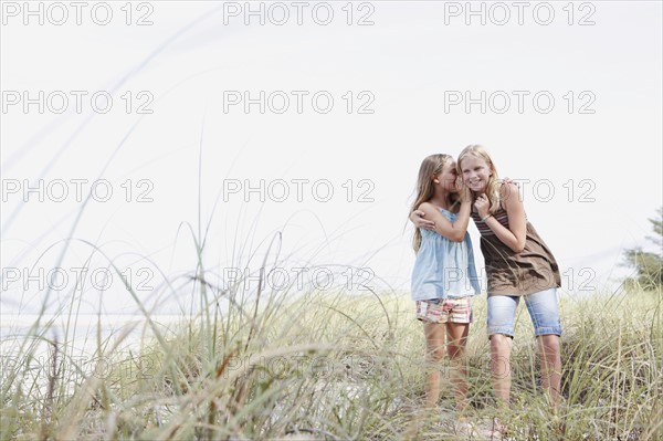 Girls telling secrets on grassy sand dune. Date : 2008