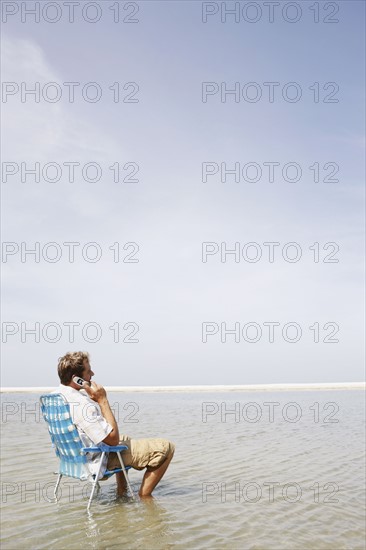 Man talking on cell phone in middle of water. Date : 2008