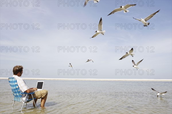 Man using laptop in middle of water. Date : 2008