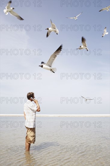 Man talking on cell phone in middle of water. Date : 2008